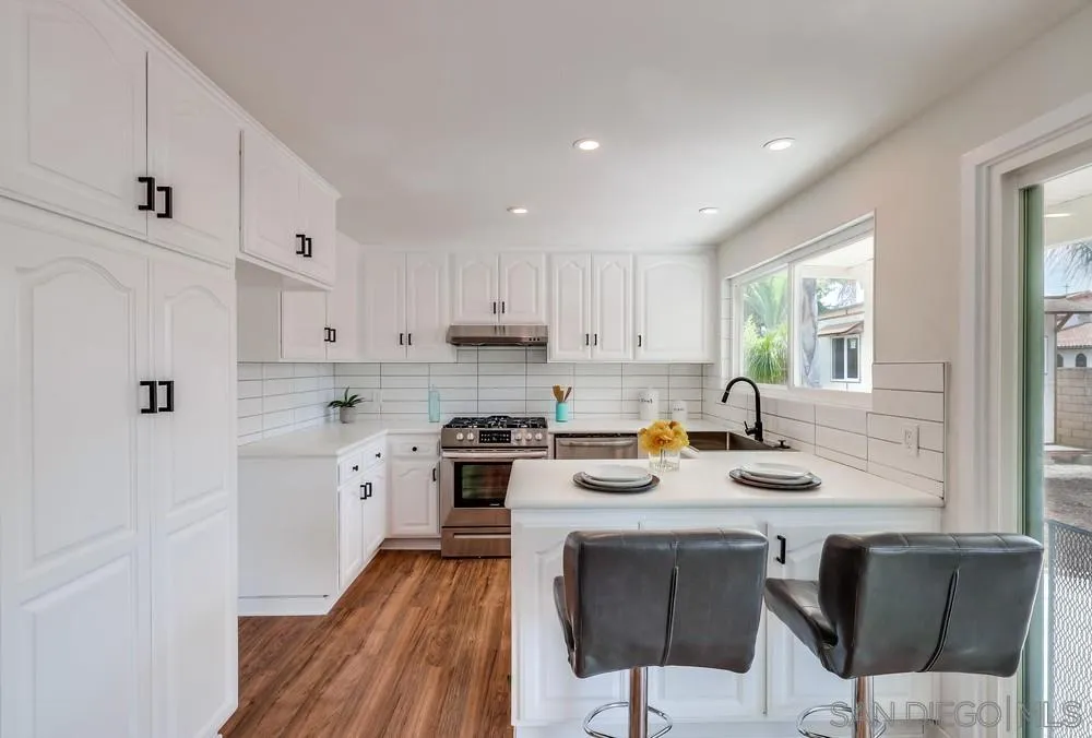 13362 Carriage Road Poway, CA 92064 - Photo 14 of 39 a kitchen with stainless steel appliances granite countertop a stove a sink a refrigerator and white cabinets with wooden floor
