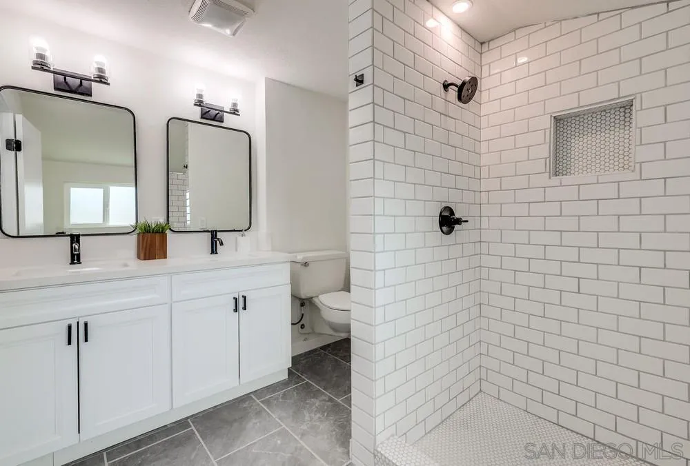 13362 Carriage Road Poway, CA 92064 - Photo 20 of 39 a bathroom with a double vanity sink a toilet a mirror and shower