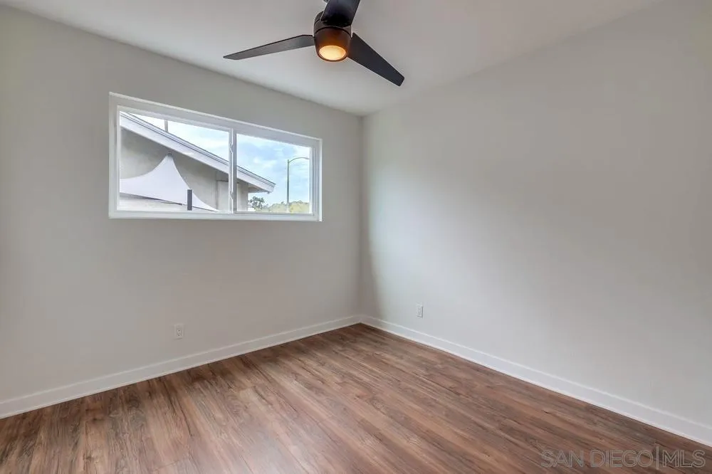 13362 Carriage Road Poway, CA 92064 - Photo 22 of 39 an empty room with wooden floor chandelier fan and windows