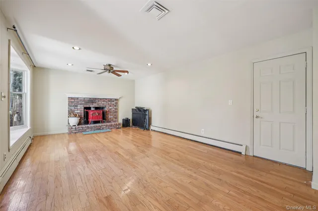 an empty room with wooden floor fireplace and windows