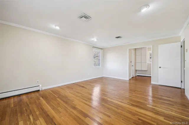 a view of empty room with wooden floor and fan