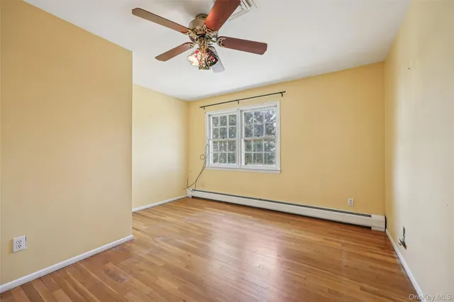 an empty room with wooden floor fan and windows