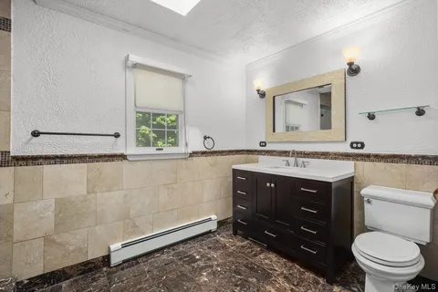 a bathroom with a granite countertop toilet sink and mirror