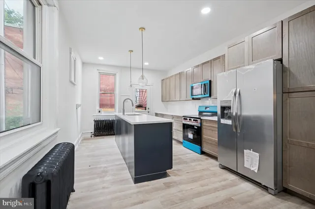 a kitchen with kitchen island a counter top space a sink stainless steel appliances and cabinets