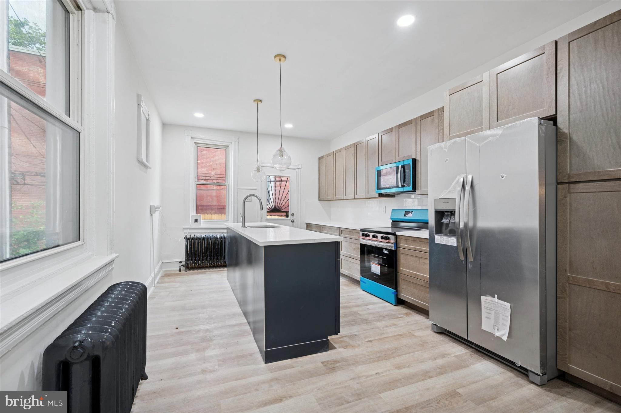 5457 Cedar Avenue Philadelphia, PA 19143 - Photo 11 of 29 a kitchen with kitchen island a counter top space a sink stainless steel appliances and cabinets