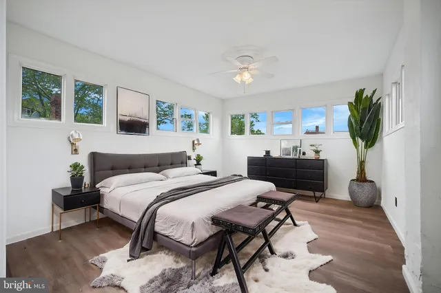 a bedroom with a bed table chair and a potted plant