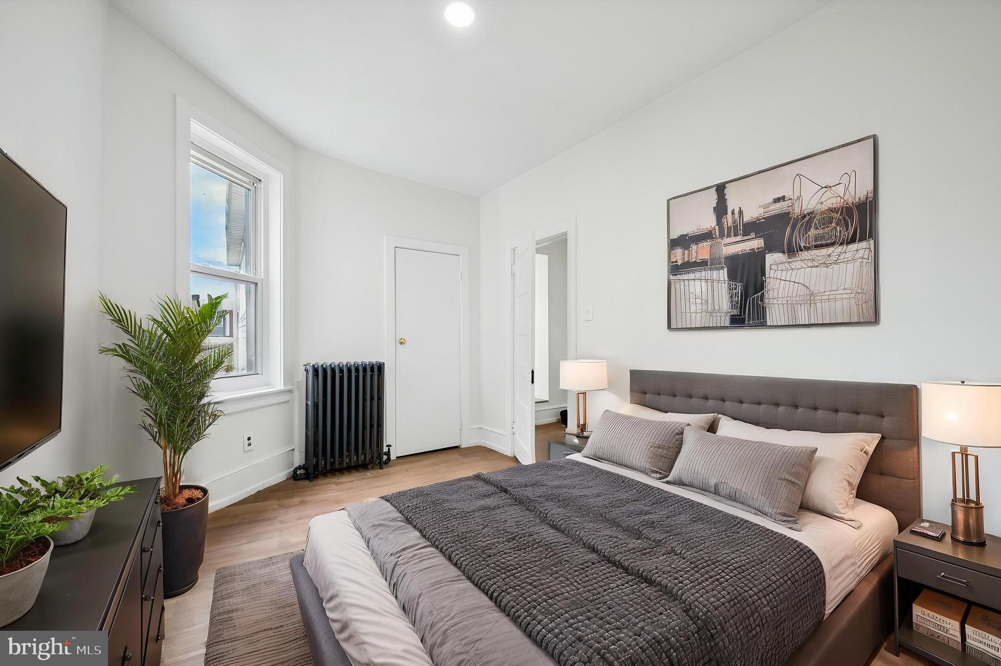 5457 Cedar Avenue Philadelphia, PA 19143 - Photo 17 of 29 a bedroom with a large bed and a potted plant