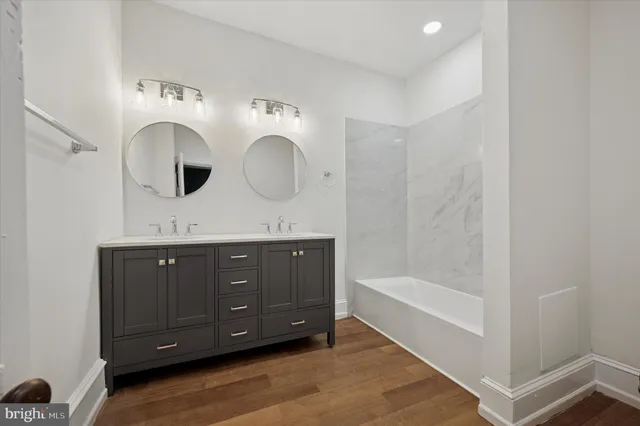 a bathroom with a double vanity sink mirror and bathtub