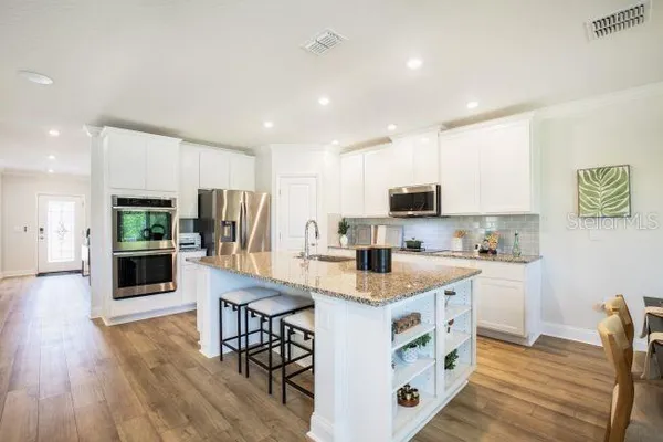 a kitchen with stainless steel appliances granite countertop a table chairs sink and cabinets