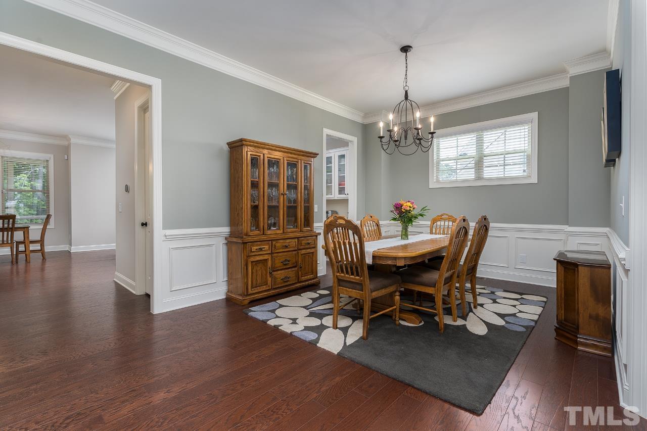 4813 Sunset Fairways Drive Apex, NC 27539 - Photo 11 of 44 a dining room with wooden floor a chandelier a wooden table and chairs