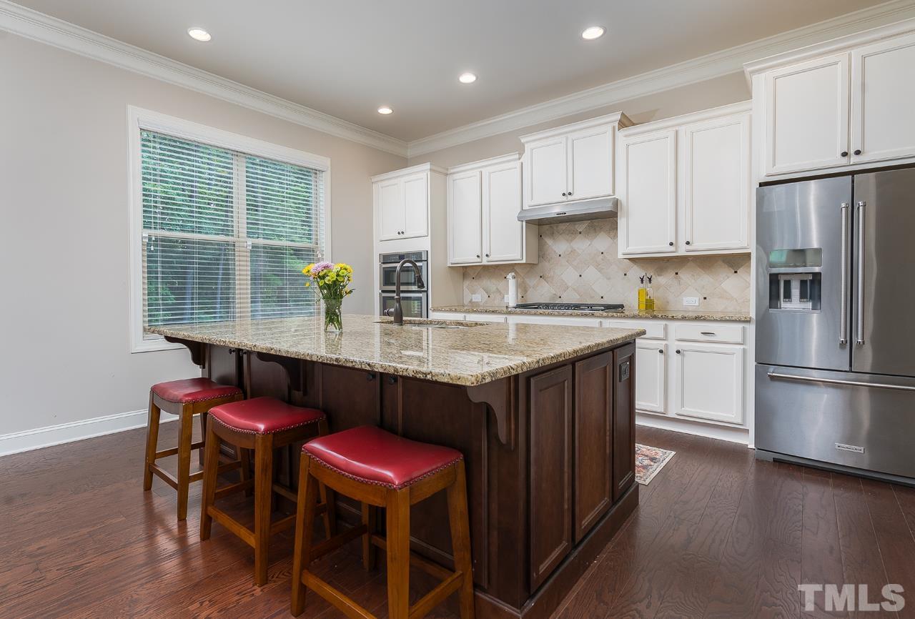 4813 Sunset Fairways Drive Apex, NC 27539 - Photo 13 of 44 a kitchen with stainless steel appliances granite countertop a stove a refrigerator a sink a dining table and chairs