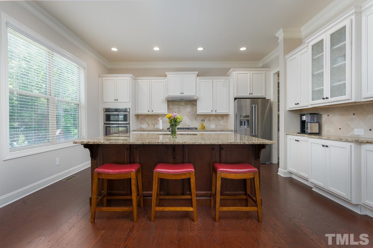 4813 Sunset Fairways Drive Apex, NC 27539 - Photo 14 of 44 a kitchen with refrigerator cabinets dining table and chairs