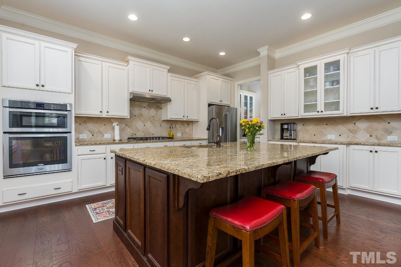 4813 Sunset Fairways Drive Apex, NC 27539 - Photo 16 of 44 a kitchen with stainless steel appliances granite countertop a kitchen island a stove a cabinets a sink and a refrigerator