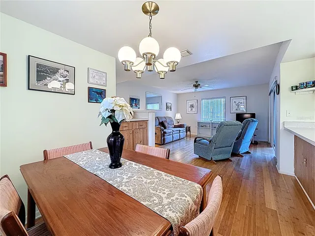 a dining room with wooden floor a chandelier a wooden table and chairs