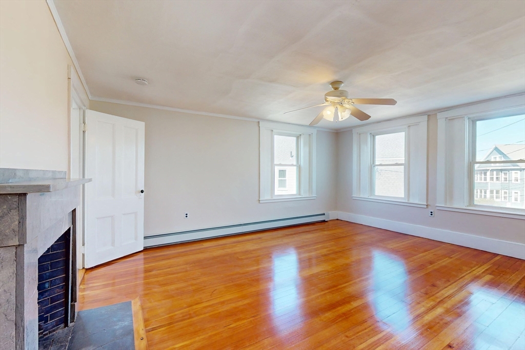 18 Faneuil Road, Unit 18 Waltham, MA 02452 - Photo 13 of 20 an empty room with wooden floor chandelier fan and windows