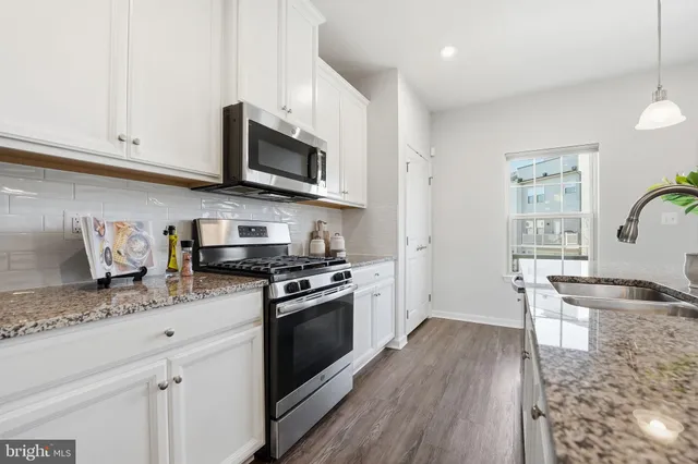 a kitchen with stainless steel appliances granite countertop a stove a sink and a microwave