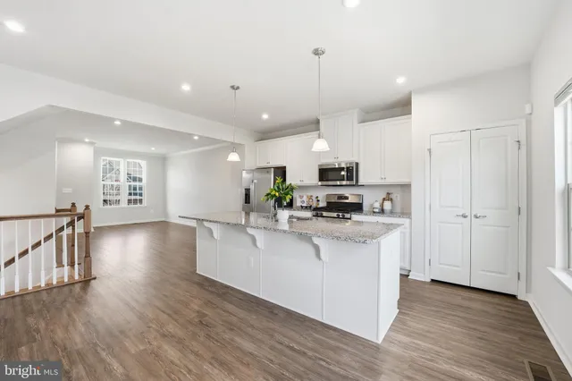 a kitchen with stainless steel appliances a stove top oven a sink a refrigerator and white cabinets with wooden floor