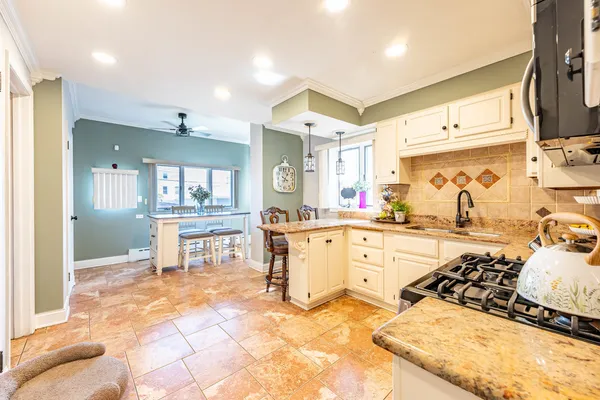 a kitchen with stainless steel appliances kitchen island granite countertop a table chairs sink and cabinets
