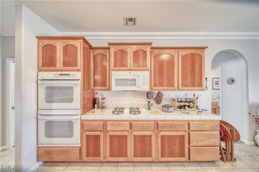 660 Indian Road Pahrump, NV 89048 - Photo 29 of 54 Kitchen with arched walkways, white Kenmore appliances, double electric ovens, crown moulding, propane fed cooktop.