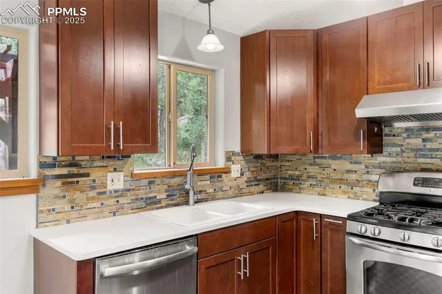 a kitchen with stainless steel appliances granite countertop wooden cabinets a sink a stove and a window