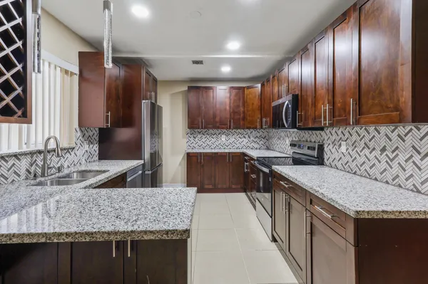 a kitchen with stainless steel appliances granite countertop wooden cabinets and sink