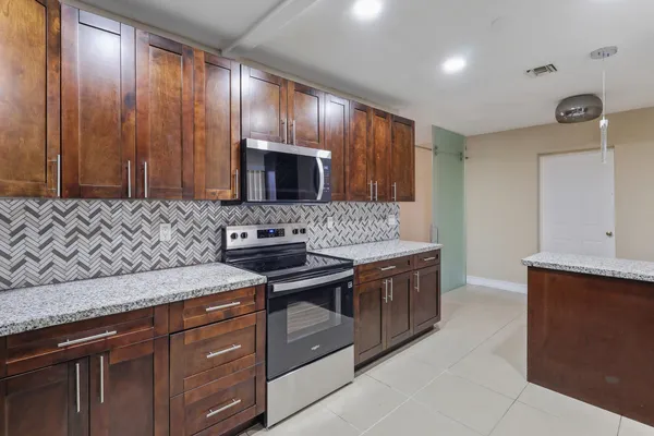 a kitchen with granite countertop stainless steel appliances a sink stove and refrigerator