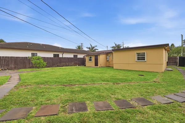 a view of a house with a yard and potted plants