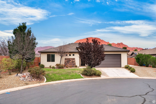 11 East 640 South Ivins, UT 84738 - Photo 41 of 44 Stucco exterior with stone accents, attached garage, concrete driveway, tiled roof, and xeriscaped and lawn landscaping