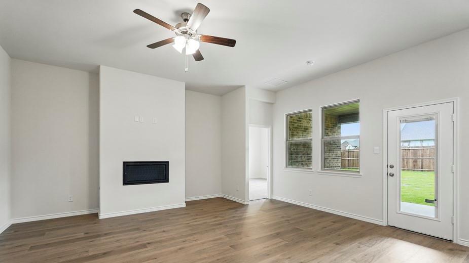 4162 Waldron Trail Forney, TX 75126 - Photo 14 of 29 Spacious living area featuring wood-finish flooring, an integrated fireplace, and a ceiling fan with light fixture