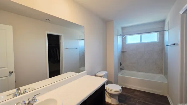 a bathroom with a granite countertop sink toilet a large mirror a bathtub and shower