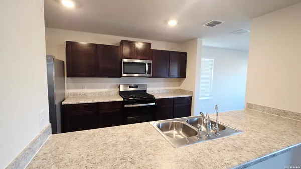 a kitchen with granite countertop a refrigerator stove top oven and sink