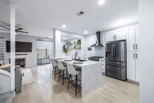 a kitchen with a refrigerator a stove top oven a sink dishwasher and white cabinets with wooden floor