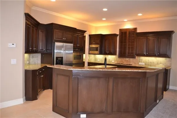 a kitchen with kitchen island granite countertop wooden cabinets and a sink