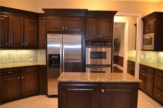 a kitchen with granite countertop a refrigerator and a stove top oven
