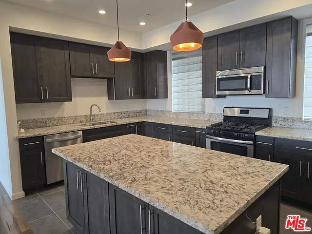 a kitchen with a stove a sink a microwave a refrigerator and cabinets