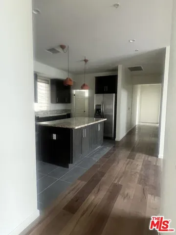 a kitchen with stainless steel appliances kitchen island granite countertop a sink and a refrigerator