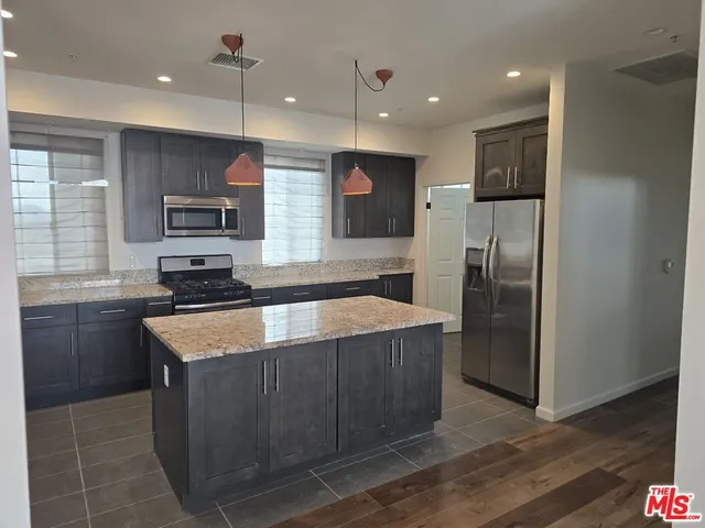 a kitchen with stainless steel appliances granite countertop wooden cabinets and a refrigerator