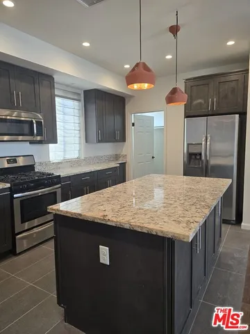 a kitchen with stainless steel appliances kitchen island granite countertop a stove a sink and a refrigerator
