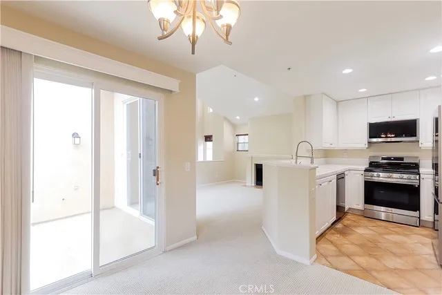 a view of a kitchen with a sink and dishwasher a refrigerator with white cabinets