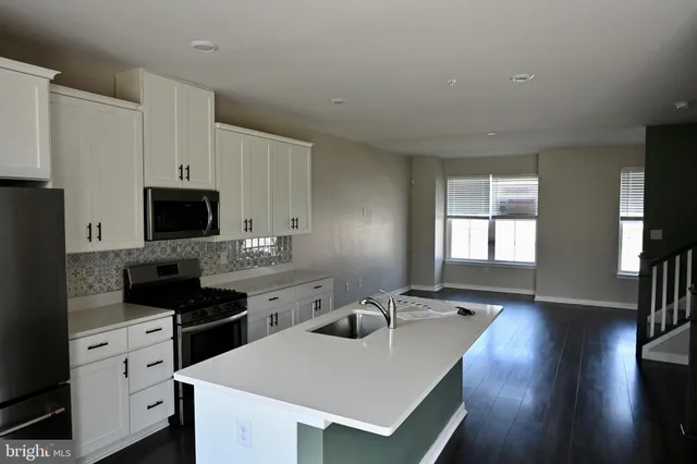 a kitchen with a sink dishwasher a stove and white cabinets with wooden floor