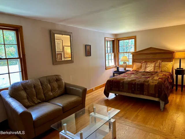 a bedroom with a bed couch and windows