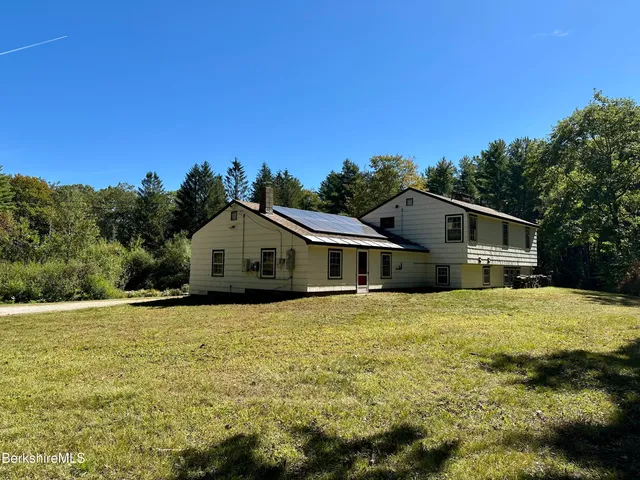 a front view of house with yard and trees in the background