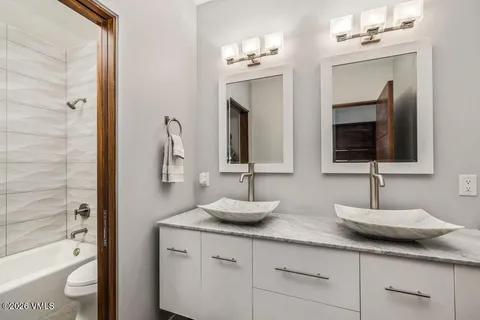 a bathroom with double vanity a toilet a mirror and a bathtub
