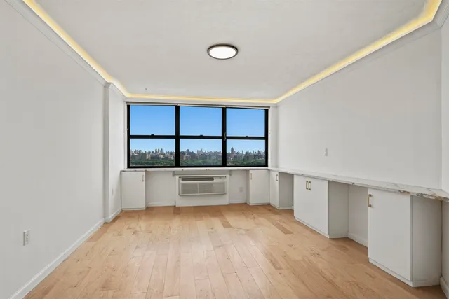a view of an empty room with window and wooden floor
