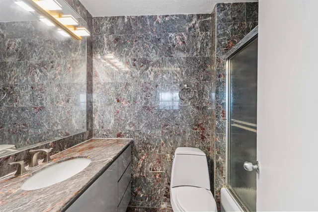 a bathroom with a granite countertop toilet sink and mirror
