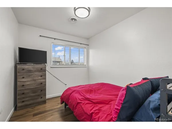 a view of a bedroom with a bed and wooden floor