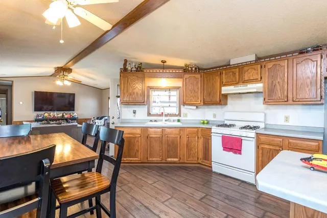 a kitchen with stainless steel appliances granite countertop a kitchen island hardwood floor sink stove dining table and chairs