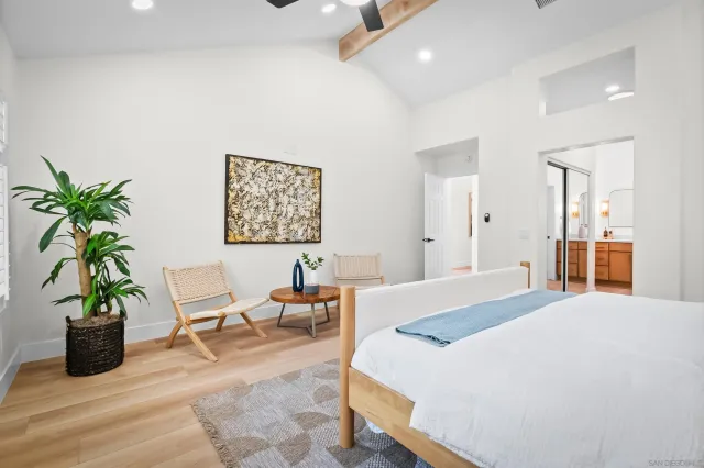 a bedroom with a large bed a potted plant and a large window