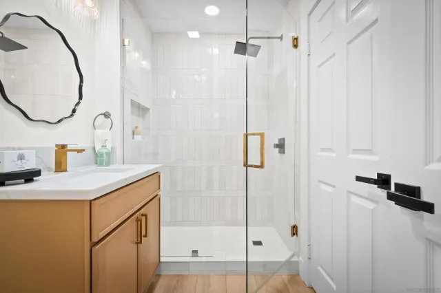 a bathroom with a granite countertop sink a mirror and a shower