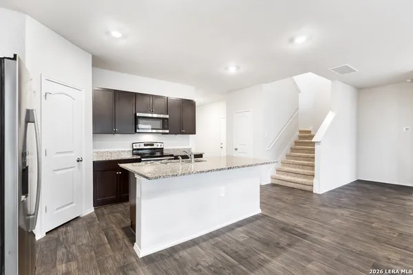 a kitchen with granite countertop a stove a sink and a refrigerator